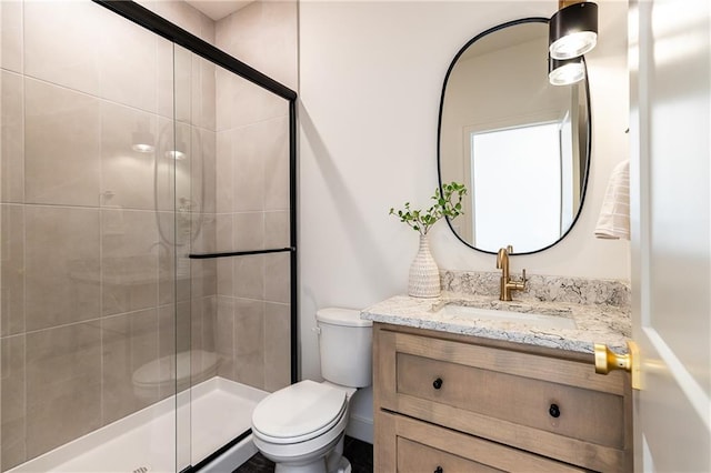 bathroom with vanity, toilet, and a shower with door