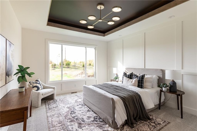 bedroom with light carpet and a raised ceiling