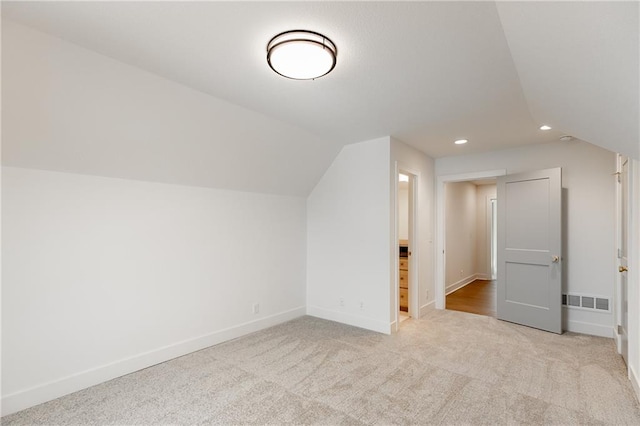 bonus room featuring vaulted ceiling and light colored carpet