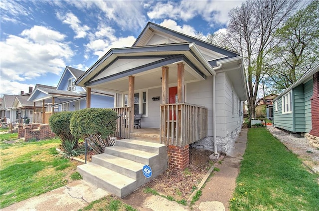 bungalow-style house featuring covered porch and a front lawn