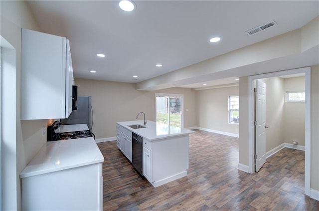 kitchen featuring dark wood-type flooring, sink, an island with sink, dishwasher, and stove