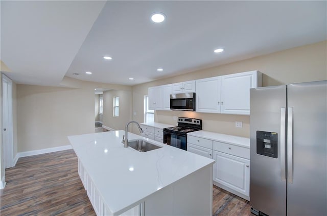 kitchen with appliances with stainless steel finishes, white cabinetry, dark hardwood / wood-style flooring, and an island with sink