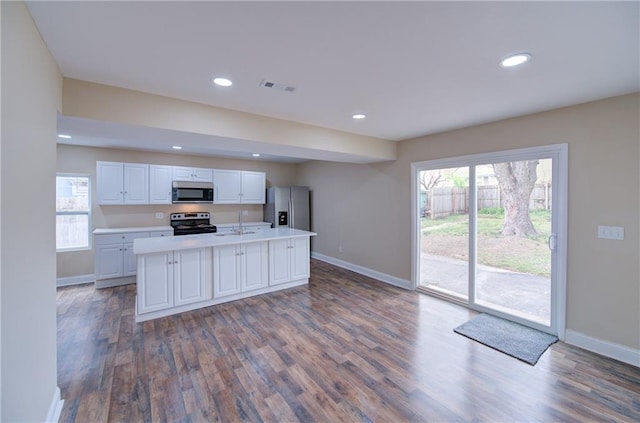 kitchen featuring appliances with stainless steel finishes, hardwood / wood-style flooring, an island with sink, and white cabinets