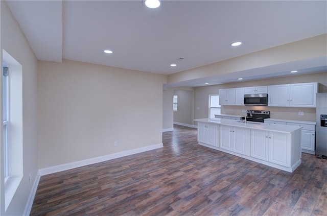 kitchen with white cabinets, a kitchen island with sink, stainless steel appliances, and dark wood-type flooring