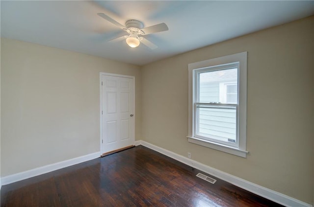 empty room with dark hardwood / wood-style floors, a healthy amount of sunlight, and ceiling fan