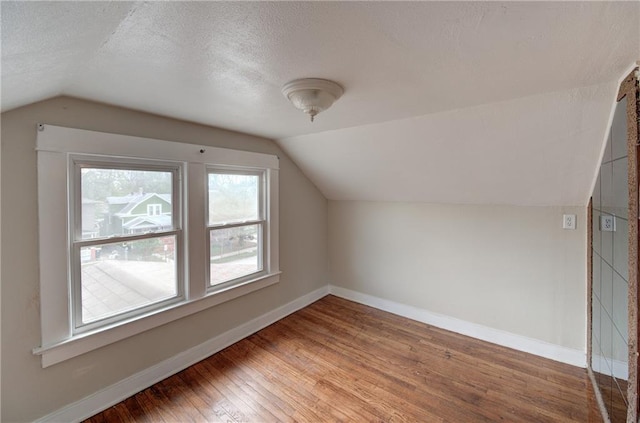 bonus room with dark hardwood / wood-style flooring, a textured ceiling, and vaulted ceiling