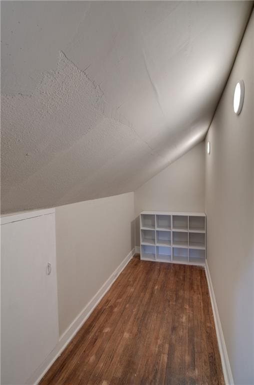 bonus room with lofted ceiling, dark hardwood / wood-style floors, and a textured ceiling