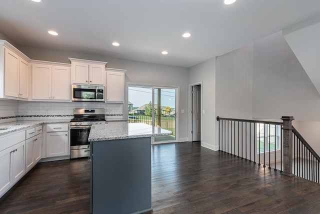 kitchen featuring a kitchen island, dark hardwood / wood-style floors, stainless steel appliances, white cabinets, and light stone counters