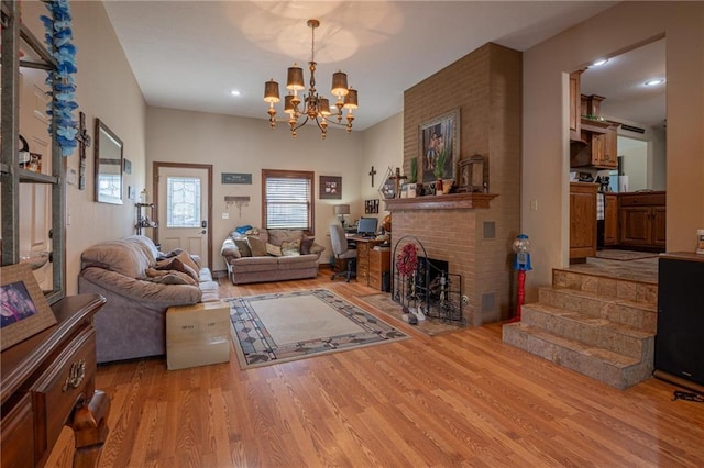 living room with an inviting chandelier, a fireplace, and light hardwood / wood-style flooring