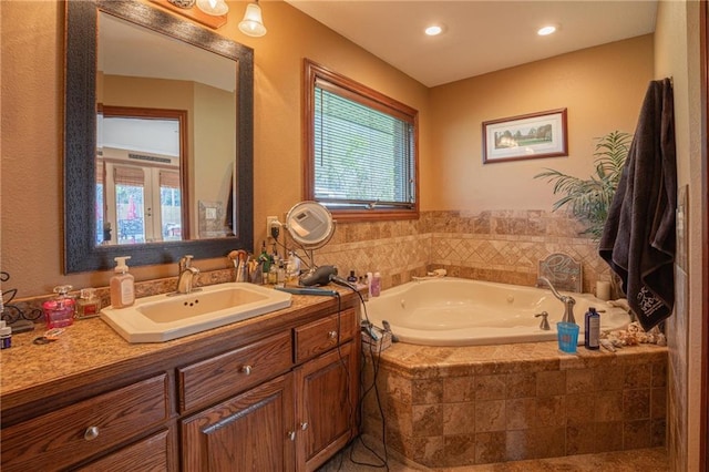 bathroom with vanity and tiled tub