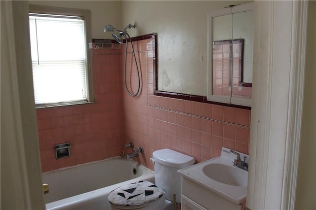 full bathroom featuring tile walls, vanity, tiled shower / bath combo, and toilet