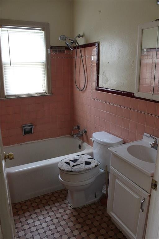 full bathroom with tiled shower / bath combo, vanity, tile walls, and toilet