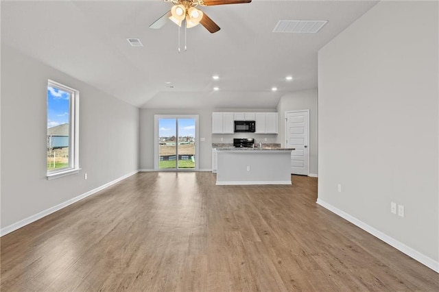 unfurnished living room with light hardwood / wood-style floors, vaulted ceiling, and ceiling fan