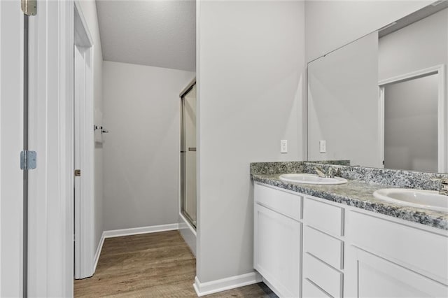 bathroom featuring hardwood / wood-style flooring, vanity, an enclosed shower, and a textured ceiling