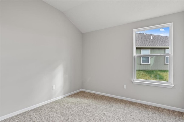 carpeted spare room with vaulted ceiling