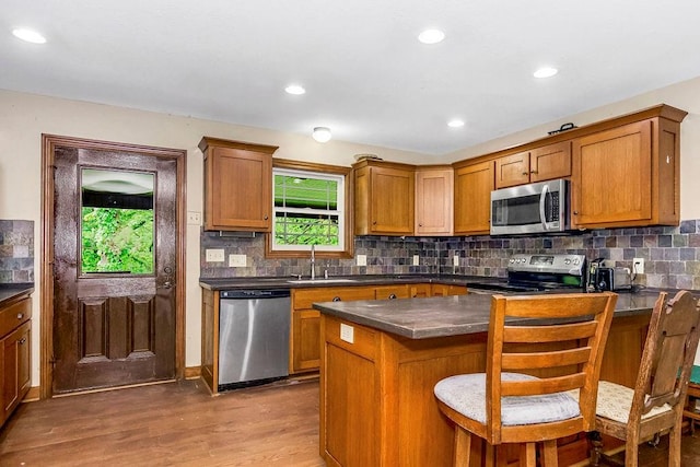 kitchen with backsplash, wood-type flooring, appliances with stainless steel finishes, and sink