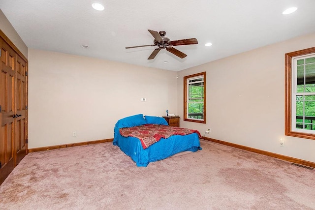 carpeted bedroom featuring ceiling fan, multiple windows, and a closet