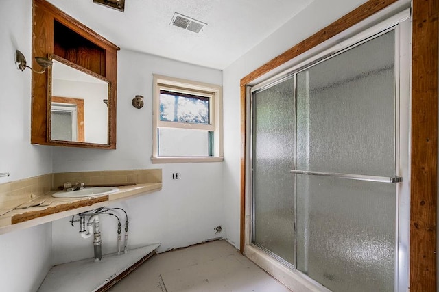 bathroom with a shower with door and sink