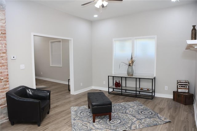 living room with hardwood / wood-style flooring, brick wall, and ceiling fan