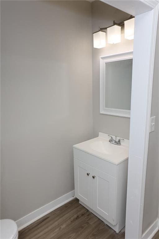 bathroom with wood-type flooring, vanity, and toilet