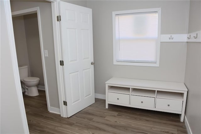 unfurnished bedroom featuring ensuite bath, dark wood-type flooring, and multiple windows