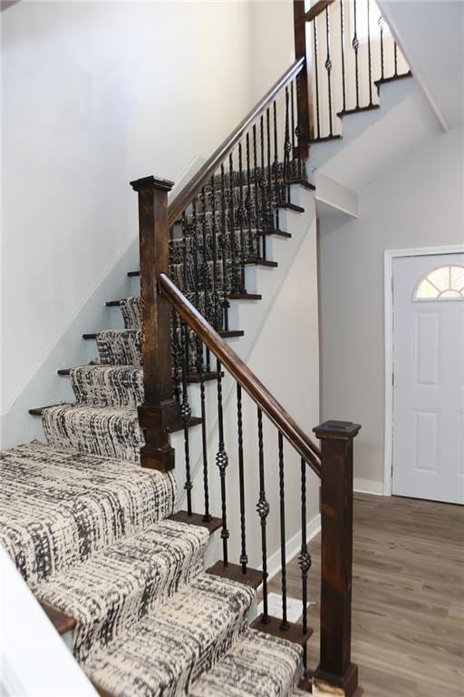 stairs featuring wood-type flooring and a high ceiling