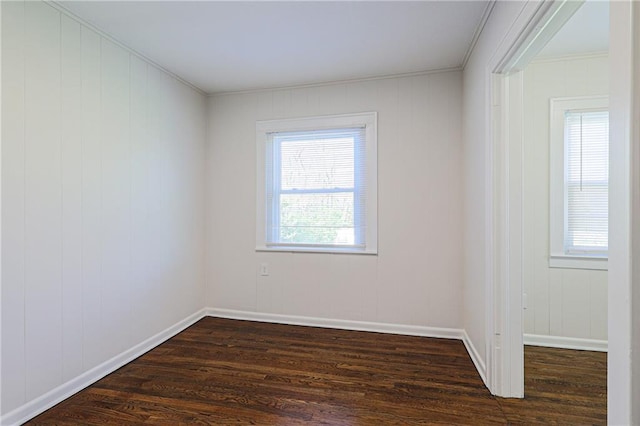 empty room with ornamental molding and dark hardwood / wood-style floors