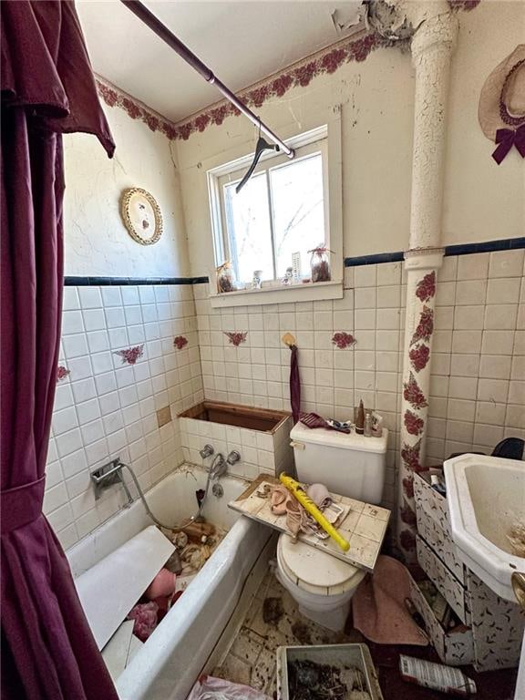 full bathroom featuring toilet, tile walls, shower / bath combo with shower curtain, and sink