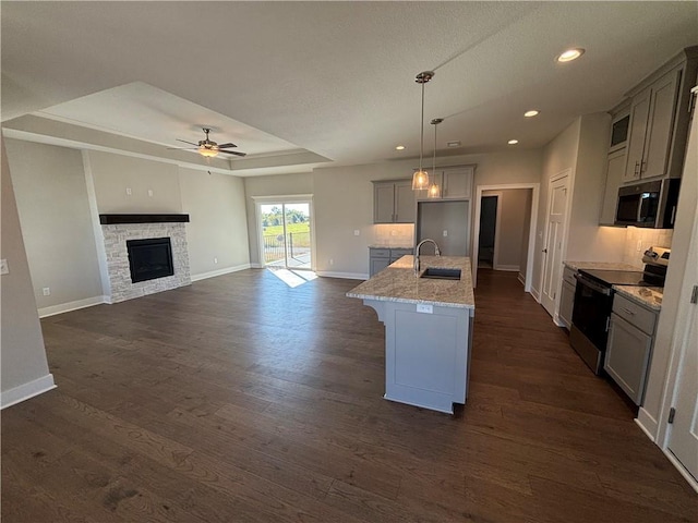 kitchen with gray cabinets, appliances with stainless steel finishes, sink, hanging light fixtures, and a kitchen island with sink