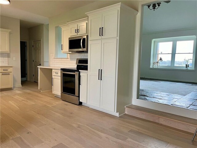 15523A W 303rd St, Paola, KS 66071 - kitchen with light hardwood / wood-style floors, backsplash, white cabinetry, and stainless steel appliances