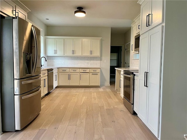 15523A W 303rd St, Paola, KS 66071 - kitchen featuring backsplash, light hardwood / wood-style flooring, stainless steel appliances, and white cabinets