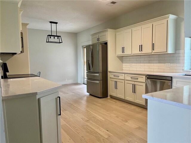15523A W 303rd St, Paola, KS 66071 - kitchen featuring decorative light fixtures, appliances with stainless steel finishes, backsplash, white cabinets, and light wood-type flooring