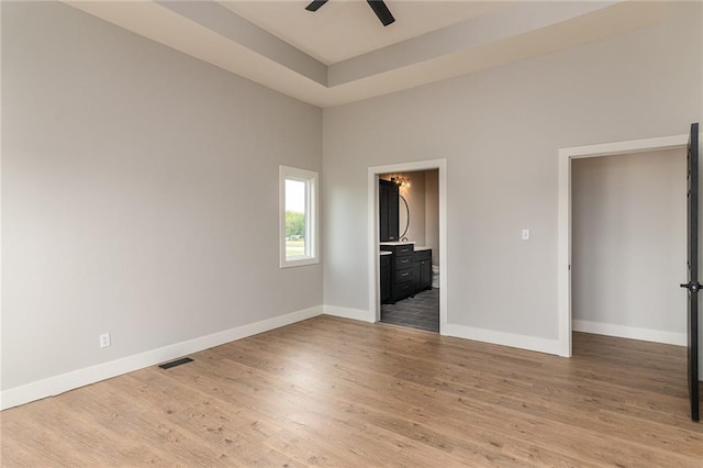 149 S Linn Valley Dr, Linn Valley, KS 66040 - unfurnished bedroom with light wood-style floors, baseboards, ensuite bathroom, a raised ceiling, and a ceiling fan