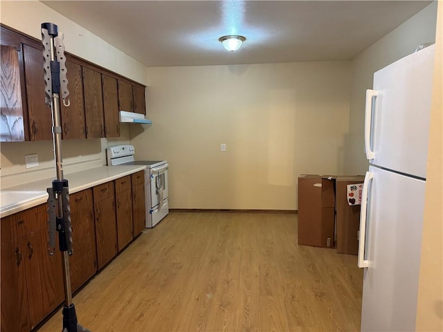 kitchen with dark brown cabinets, light hardwood / wood-style floors, and white appliances