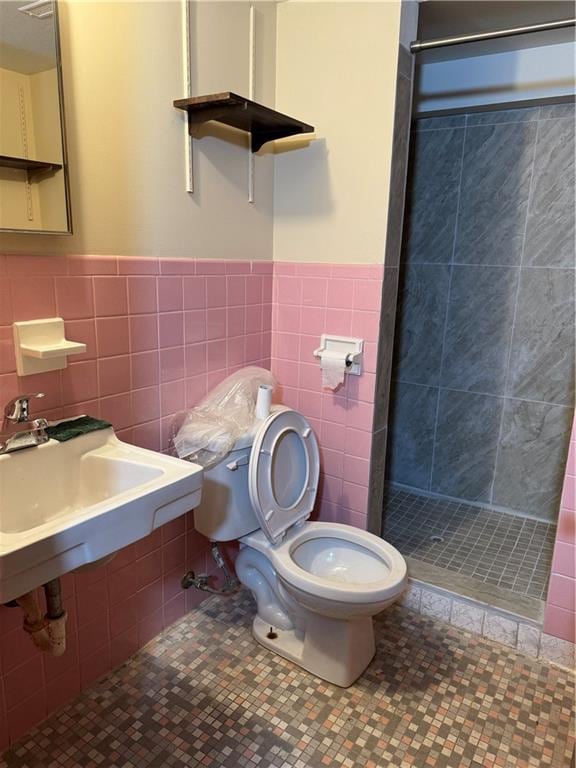 bathroom featuring tile flooring, tile walls, tiled shower, and toilet