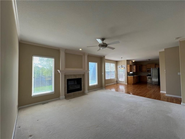 unfurnished living room featuring hardwood / wood-style floors, ceiling fan, a tile fireplace, and a healthy amount of sunlight