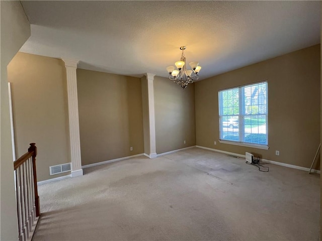 spare room with ornate columns, a notable chandelier, and carpet floors