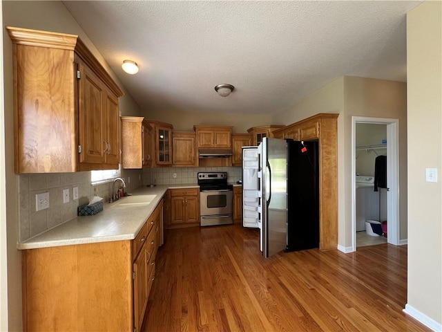 kitchen with backsplash, hardwood / wood-style flooring, stainless steel appliances, sink, and a textured ceiling