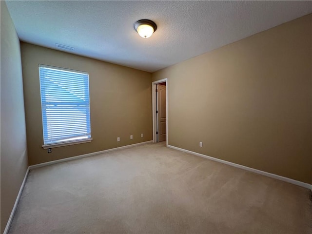 spare room featuring a textured ceiling and light carpet