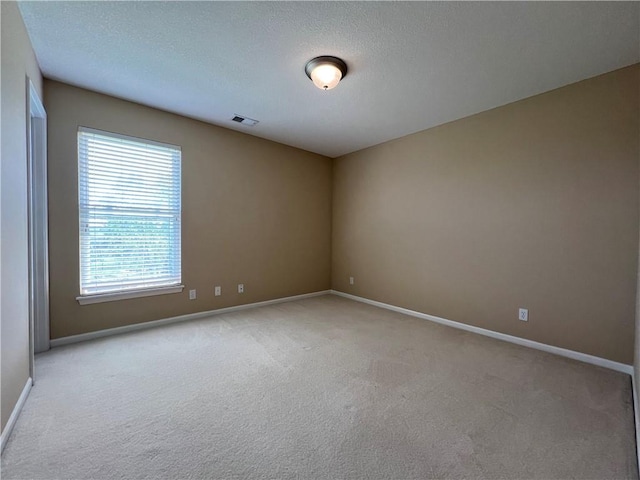 empty room featuring a textured ceiling and light colored carpet