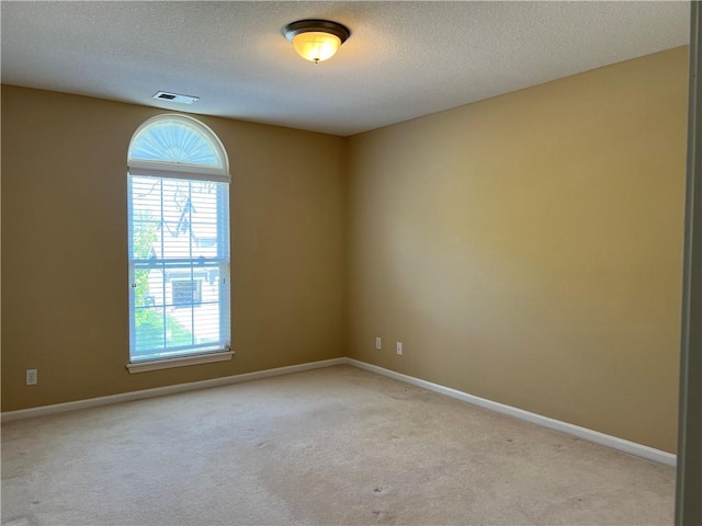 carpeted empty room with a textured ceiling