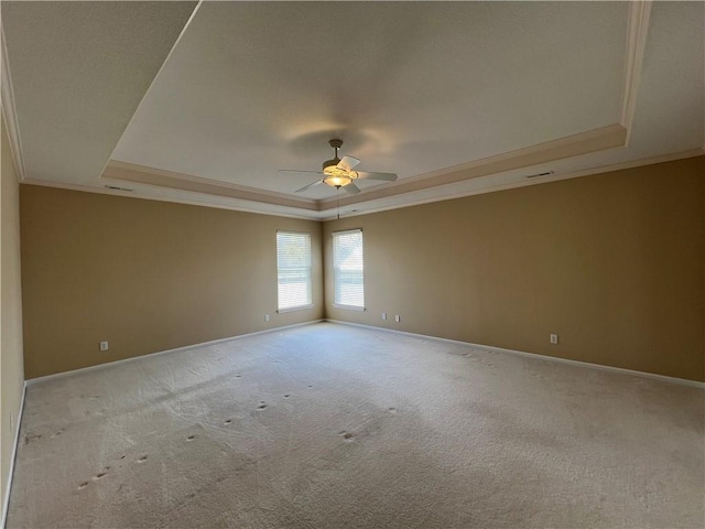 spare room featuring a tray ceiling, ceiling fan, and light colored carpet