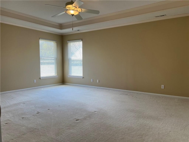 carpeted spare room with a raised ceiling, visible vents, ornamental molding, ceiling fan, and baseboards