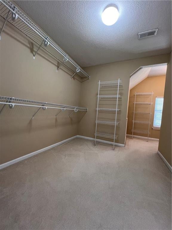 spacious closet with lofted ceiling and carpet floors