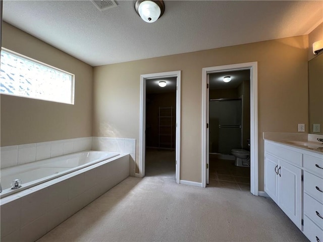 full bathroom featuring vanity, toilet, separate shower and tub, and a textured ceiling