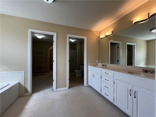 bathroom with vanity, a textured ceiling, toilet, and tiled bath