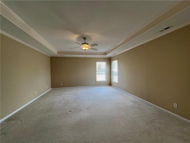 unfurnished room with light colored carpet, ceiling fan, ornamental molding, and a tray ceiling