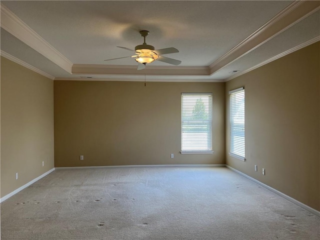 carpeted spare room with ceiling fan, a raised ceiling, and ornamental molding