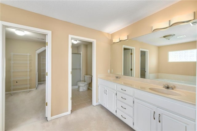 full bath with double vanity, a spacious closet, a textured ceiling, and a sink