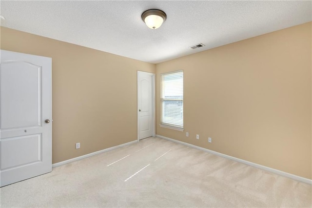 spare room with carpet floors, visible vents, baseboards, and a textured ceiling